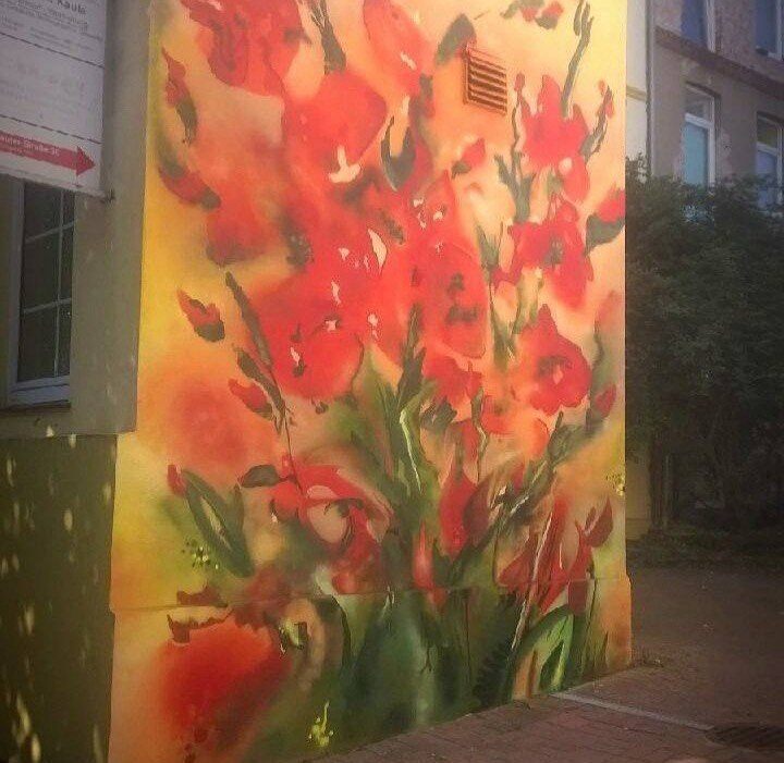 Wandbild mit roten Mohn- und Gladiolenblüten an einer Hauswand